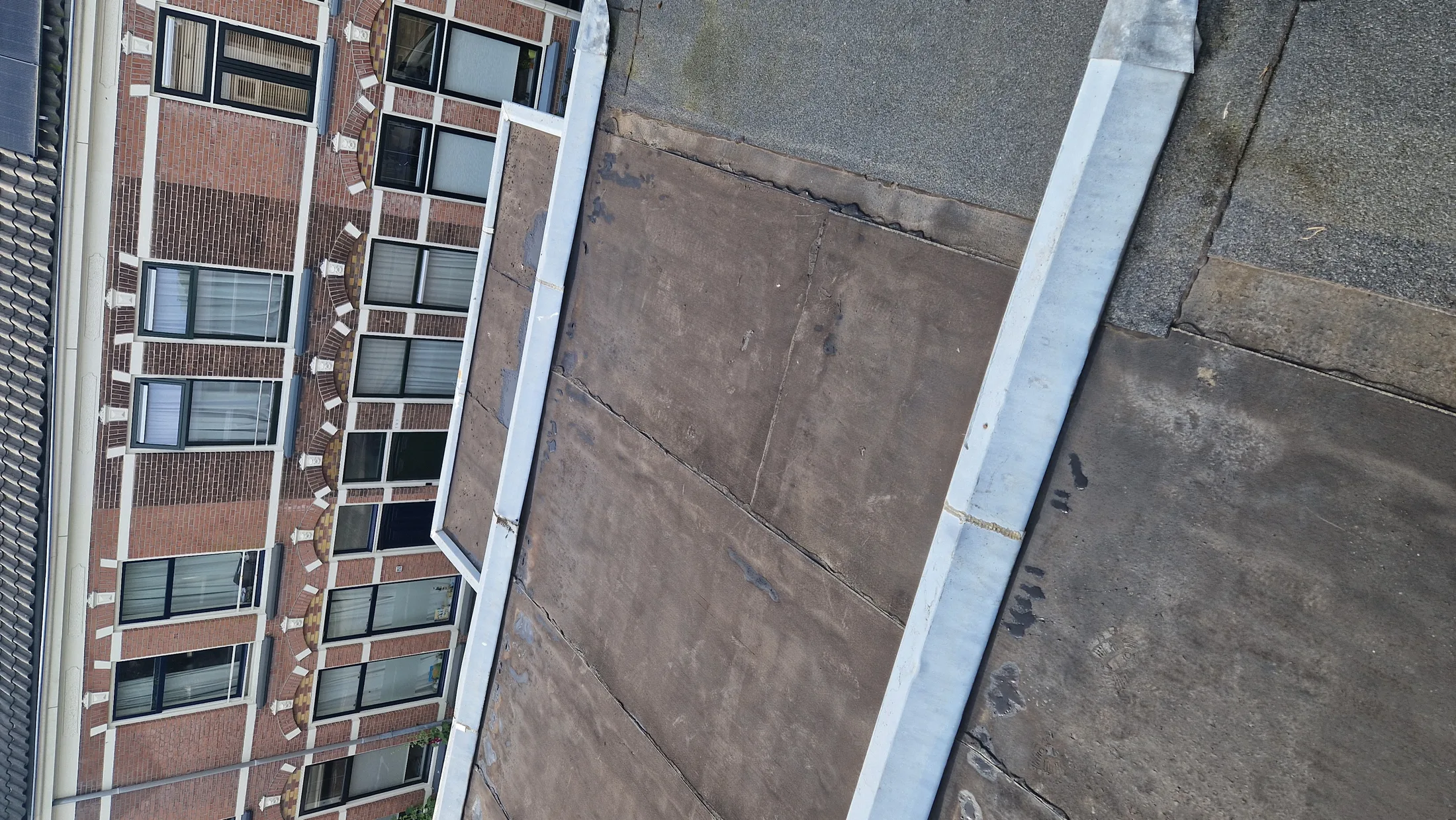 Verouderd bitumen in detail bij hybride dakcoating op particulier bitumendak in amersfoort