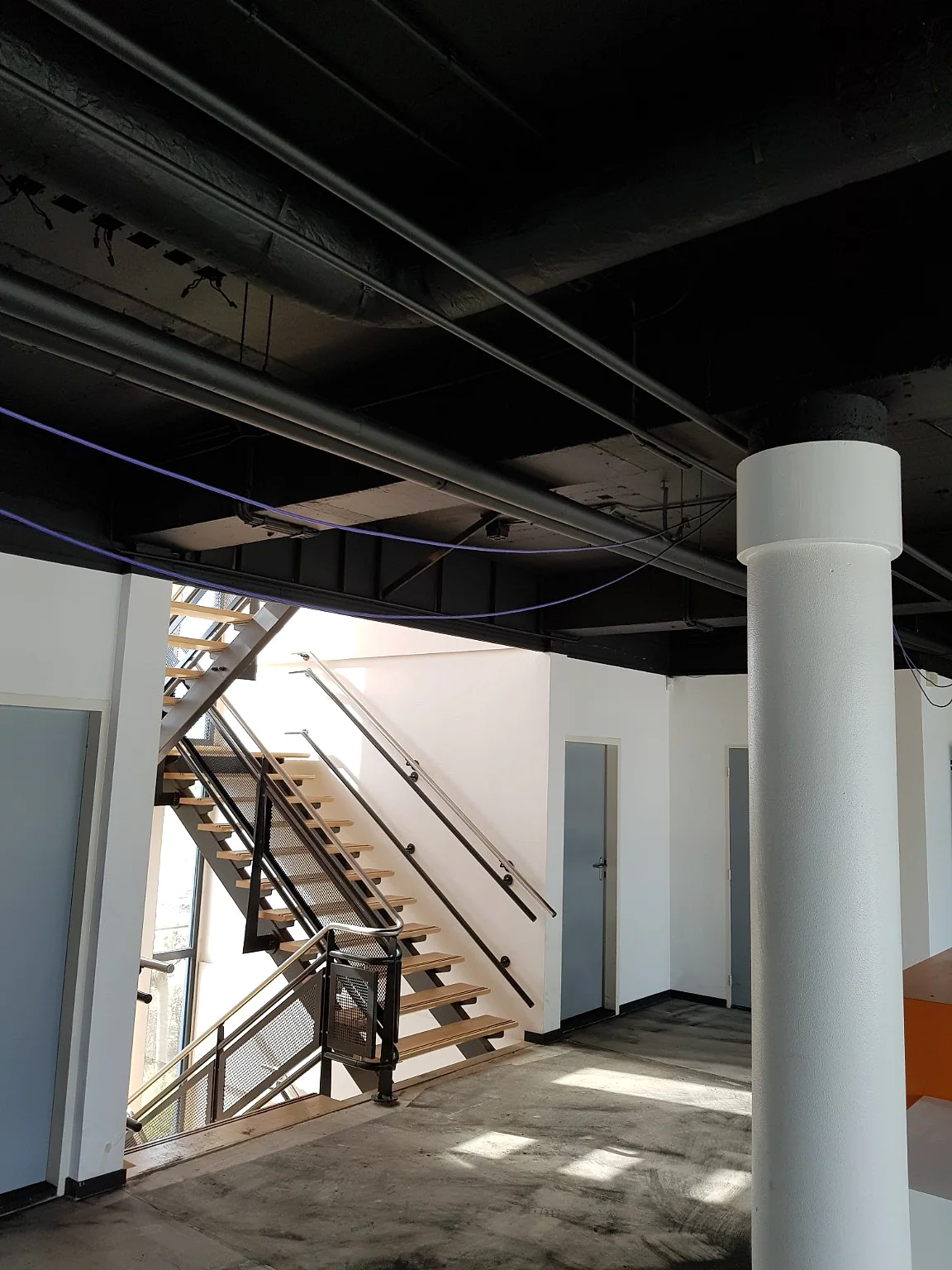 Zwart gespoten open plafond in een zakelijk kantorencomplex